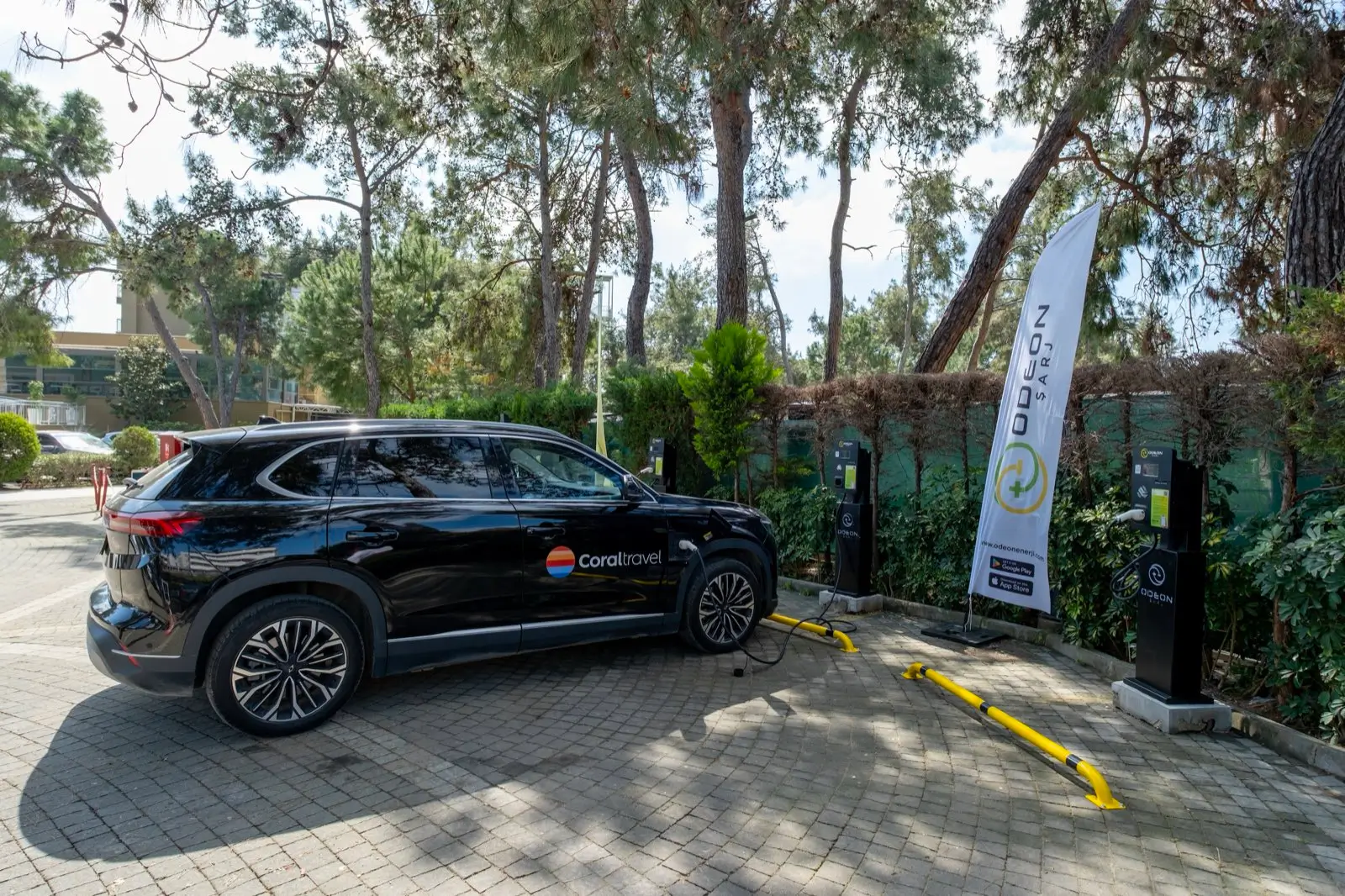 Elektryczny samochód Coral Travel przy stacji ładowania